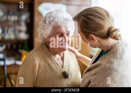 Freundliche Krankenschwester, die eine ältere Dame unterstützt Stockfoto