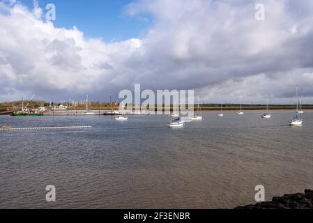 North Fambridge Flussufer am Fluss Crouch von South Fambridge, Essex, Großbritannien aus gesehen. Festfahrende Schiffe und Anlegesteg. Stark bewölkt, helles Licht Stockfoto