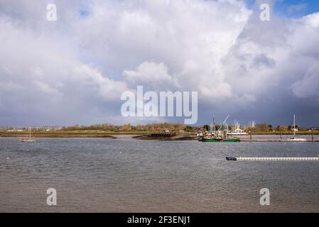 North Fambridge Flussufer am Fluss Crouch von South Fambridge, Essex, Großbritannien aus gesehen. Festfahrende Schiffe und Anlegesteg. Stark bewölkt, helles Licht Stockfoto