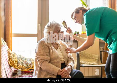 Freundliche Krankenschwester, die eine ältere Dame unterstützt Stockfoto