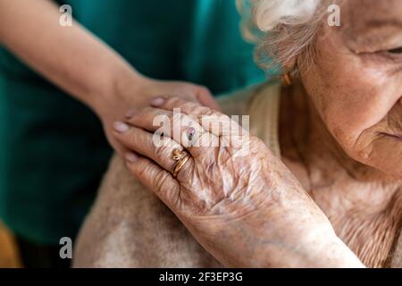 Zugeschnittenes Bild einer älteren Frau, die die Hände mit einem hält Krankenschwester Stockfoto