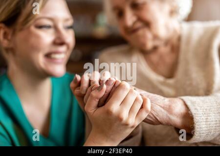 Zugeschnittenes Bild einer älteren Frau, die die Hände mit einem hält Krankenschwester Stockfoto