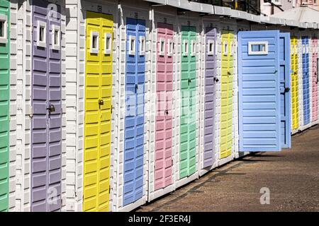 Bunte Strandhütten in einer Reihe, mit einer einzigen offenen Tür, an der Promenade bei Lyme Regis, Jurassic Coast, Dorset Stockfoto