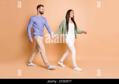 In voller Größe Profil Foto des optimistischen Paar gehen tragen Pullover Isoliert auf beigefarbenem Hintergrund Stockfoto