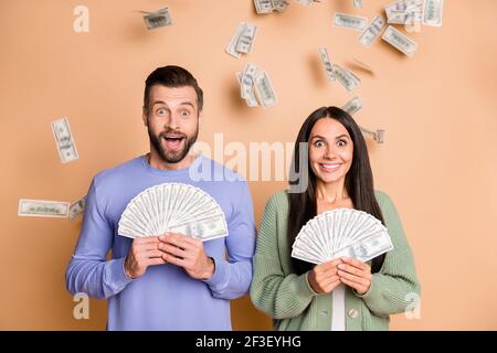 Foto von beeindruckt Paar halten Geld tragen Pullover isoliert auf Beigefarbener Hintergrund Stockfoto