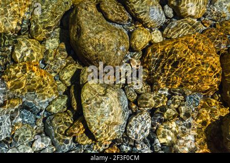 Steine unter klarem Wasser. Steine, Felsen, Kieselsteine Hintergrund.Sommer Hintergrund.schöne Natur Hintergrund. Welligkeit und Reflexion.Wandpapier. Stockfoto