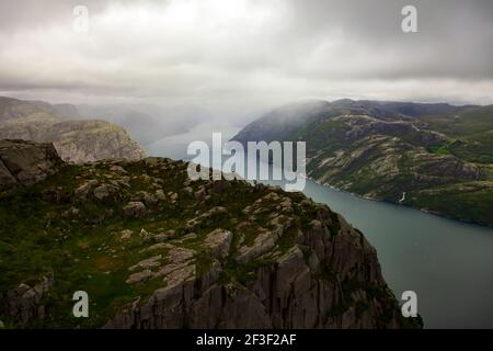 Blick auf den Fjordsee vom Pulpit Rock, Blick vom aufsteigenden Pfad, Lysefjord, Norwegen. Skandinavische Landschaft. Dramatischer nebliger Himmel. Stockfoto