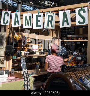 Liverpool Street, London, UK,- am 21. September 2020 UNTERSUCHT EINE Frau Vintage-Artikel auf der Theke. Spitalfields Antiquitätenmarkt. Kameras. Stockfoto