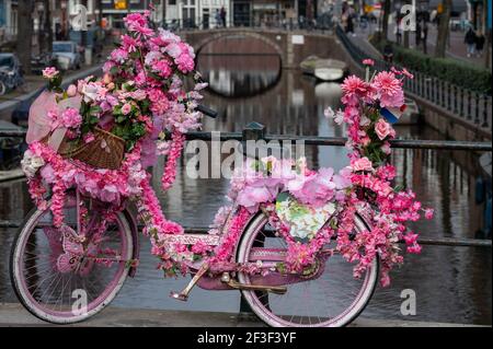 Alte vintage Frau Fahrrad mit rosa Blumen auf klein dekoriert Brücke in der Altstadt von Amsterdam Stockfoto