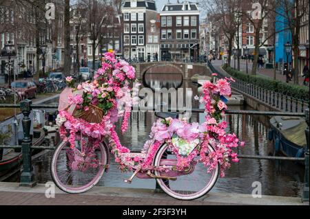 Alte vintage Frau Fahrrad mit rosa Blumen auf klein dekoriert Brücke in der Altstadt von Amsterdam Stockfoto