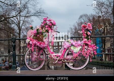 Alte vintage Frau Fahrrad mit rosa Blumen auf klein dekoriert Brücke in der Altstadt von Amsterdam Stockfoto