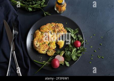 Blumenkohlsteak mit Kräutern und Gewürzen auf dunklem Hintergrund. Nahaufnahme. Stockfoto