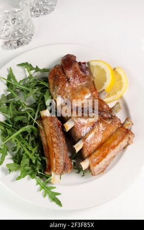 Gebratene Rippchen mit frischem Salat auf weißem Teller. Direkt darüber. Speicherplatz kopieren. Stockfoto