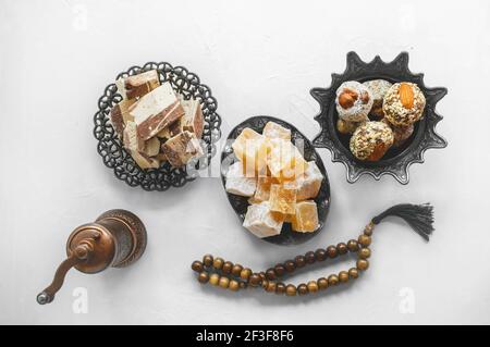 Schüssel mit verschiedenen Stücken türkischer Delight Locum und schwarzem Tee mit Minze auf hellem Hintergrund. Orientalische Süßigkeiten. Draufsicht. Stockfoto