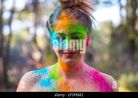 Wunderbare junge energetische Frau auf dem Holi Farbfestival der Farben im Park. Spaß im Freien. Bunte Puder färbt das Gesicht. Nahaufnahme. Stockfoto