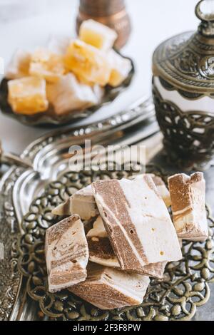 Eine Vase mit verschiedenen Halva-Stücken und orientalischen Süßigkeiten auf hellem Hintergrund. Nahaufnahme der Halva. Stockfoto