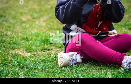 Ein Blick auf eine Person, die auf grünem Gras sitzt Stockfoto