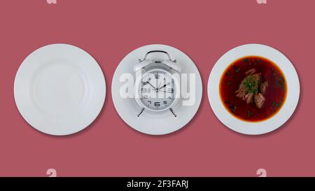 Intermittierendes Fastenkonzept. Leerer weißer Teller, Wecker und Suppe. Gesunde Ernährung Konzept. Gewichtsverlust. Draufsicht Stockfoto