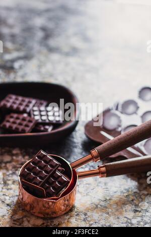 Sortiment verschiedener Schokoladensorten in geschnitztem Holzteller, mit Vintage-Requisiten auf dem Hintergrund Stockfoto