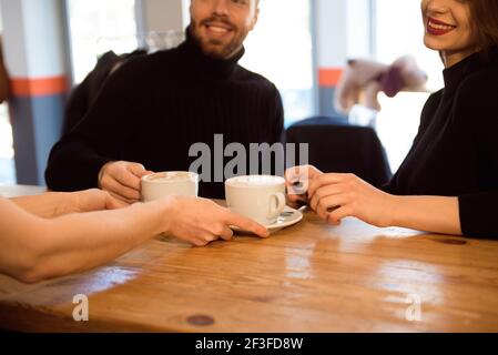Freundlicher Barkeeper, der den Gästen Espresso im Inneren eines modernen Coffee Shops serviert. Stockfoto