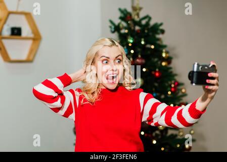 Schließen Frauenportrait mit schönem Lächeln mit Grübchen und Locken auf blondem Haar. Frau hält Kamera Dame Fotografin. Konzept des Glücks, Neujahr, Stockfoto