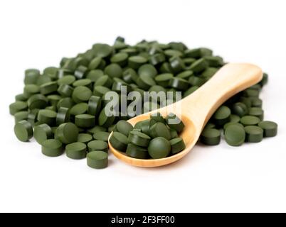 Spirulina Algentabletten mit einem Holzlöffel isoliert auf weißem Hintergrund. Nahrungsergänzungsmittel, Vitamine und Gesundheitskonzept. Stockfoto