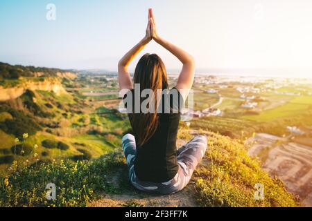 Frau praktiziert Yoga und meditiert auf der Oberseite der Berg bei Sonnenuntergang Stockfoto