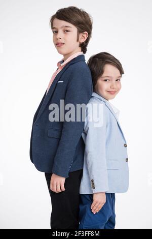 Zwei junge Jungen in Anzügen stehen zurück an den Rücken Weißer Hintergrund Stockfoto