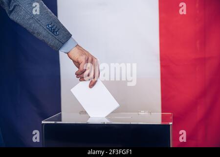 Der Wähler hält den Umschlag über der Wahlurne in der Hand. Stockfoto