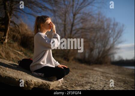 Praxis der Meditation und Interaktion mit der Natur. Mädchen in der Nähe des Flusses Stockfoto