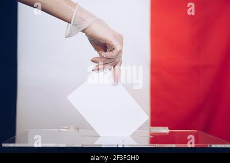 Frau Hand in medizinischen Handschuh werfen ihre Stimme in die Wahlurne. Stockfoto