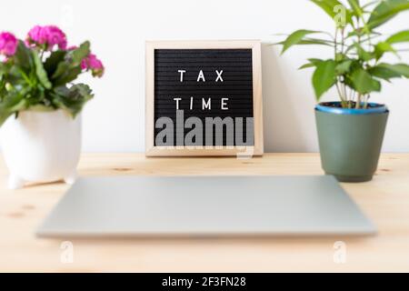 Tax Time schwarzes Filz Briefbrett, Laptop und Blumentöpfe auf dem Tisch. Geschäftssteuererklärung Konzept. Stockfoto