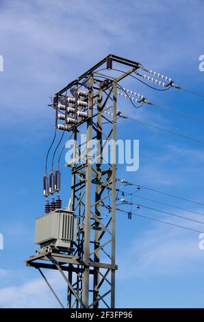 Strommast mit Transformatoren vor blauem Himmel Stockfoto