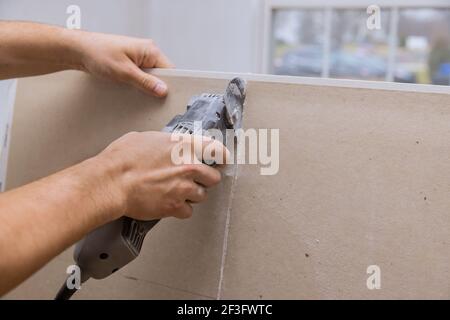 Mann schneiden Gipskarton Trockenbau mit Winkel Hand elektrische Energie Werkzeuge Stockfoto