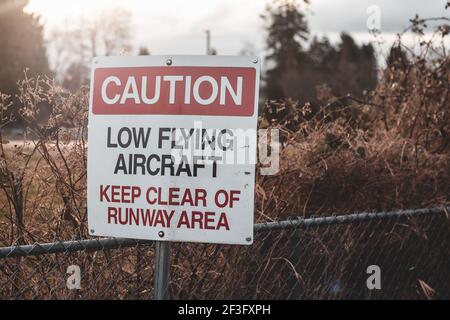 Blick auf das Schild Vorsicht Low Flying Aircraft am lokalen Flughafen in Courtenay, Kanada Stockfoto