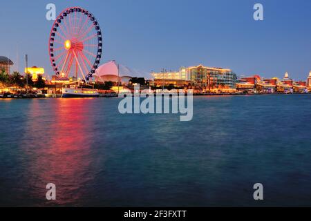 Chicago, Illinois, USA. Navy Pier während die Nacht auf die Stadt fällt, während sich das Centennial Wheel im angrenzenden Hafen widerspiegelt. Stockfoto