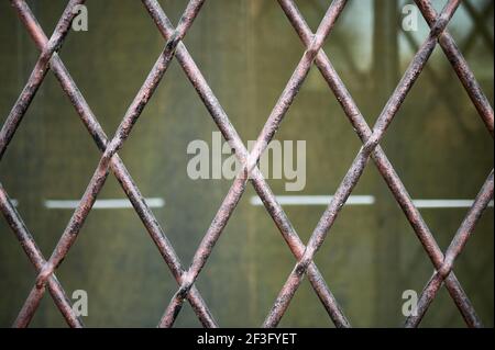 Detail eines schmiedeeisernen Kühlergrills in Form von Diamanten über einem Fenster Stockfoto