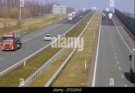 Fahrzeuge, die auf der Autobahn fahren. Sichtbare Schallschutzbarrieren trennen die Autobahn vom Wohngebiet. Stockfoto