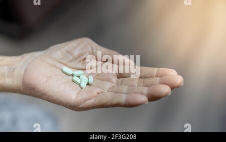 Der ältere Mann Hände Pille in seine Hand. Der Alte kümmert sich um die Gesundheit. Gesundheit und medizinisches Konzept. Stockfoto