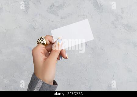 Gepflegte Womans Hand halten Postkarte auf grauem Beton Hintergrund Stockfoto