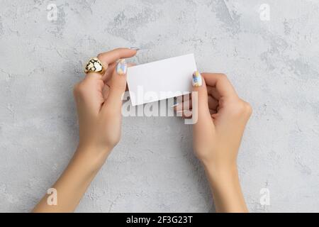 Gepflegte Womans Hand halten Postkarte auf grauem Beton Hintergrund Stockfoto