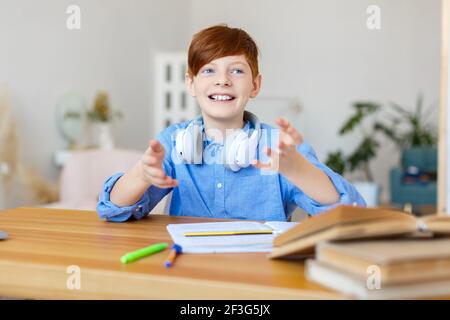 Foto eines Schülerjungen während eines Online-Gesprächs mit Klassenkameraden oder einem Lehrer. Er macht seine Hausaufgaben und hat Videoanruf. Stockfoto