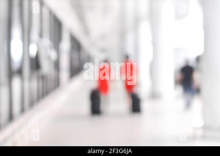 Verschwommene Leute und Flugbegleiter, die auf dem Flughafenflur herumlaufen Stockfoto