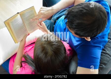 Ein Paar liest Buch, während man auf der Couch sitzt - Top Anzeigen Stockfoto