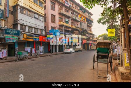 Hand gezogen Rikscha auf Stadtstraße mit Blick auf alte Wohngebäude und Geschäfte an der Esplanade Bereich von Kalkutta, Indien Stockfoto