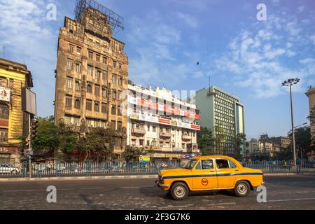 Gelbes Taxi auf der Stadtstraße mit Blick auf Bürogebäude Auf der Esplanade von Kalkutta Stockfoto