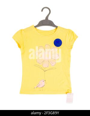 Gelbes Baumwoll-T-Shirt mit Blume und Vogel auf schwarzem Kunststoff-Kleiderbügel. Isoliert auf weißem Hintergrund. Stockfoto