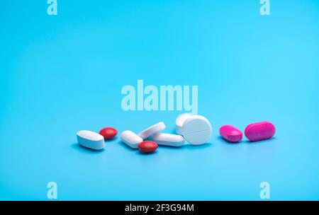 Weiße und rosa Tabletten Pillen auf blauem Hintergrund. Apothekenbanner. Pharmaindustrie. Strategie der Krankenversicherung. Pharmazeutische Fertigung. Stockfoto