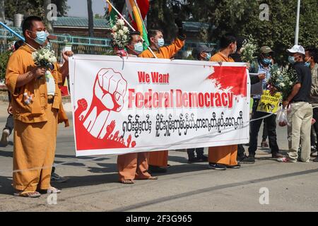 Muse, North Shan State, Myanmar. Februar 2021, 13th. Anti-Militär-Putsch Demonstranten in traditioneller Shan-Kleidung halten ein großes Banner mit der Aufschrift "Wir wollen Föderale Demokratie" in Englisch und Shan (Shan ist eine der ethnischen Minderheiten in Myanmar) während einer friedlichen Demonstration gegen den Militärputsch.EINE massive Menschenmenge ging auf die Straßen von Muse (Burmesische Grenzstadt zu China), um gegen den Militärputsch zu protestieren und die Freilassung von Aung San Suu Kyi zu fordern. Das Militär von Myanmar nahm am 01. Februar 2021 die staatliche Beraterin von Myanmar, Aung San Suu Kyi, fest und erklärte den Ausnahmezustand Stockfoto