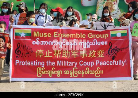 Muse, North Shan State, Myanmar. Februar 2021, 13th. Anti-Militärputsch Demonstranten halten ein großes Banner mit der Aufschrift "Muse Ensemble Group, Protesting the Military Coup peaceful" während einer friedlichen Demonstration gegen den Militärputsch.EINE massive Menge ging auf die Straßen von Muse (birmanische Grenzstadt zu China) Um gegen den Militärputsch zu protestieren und die Freilassung von Aung San Suu Kyi zu fordern. Das Militär von Myanmar nahm am 01. Februar 2021 die staatliche Beraterin von Myanmar Aung San Suu Kyi fest und erklärte den Ausnahmezustand, während sie die Macht im Land für ein Jahr nach dem Verlust der Wahl ergattete Stockfoto